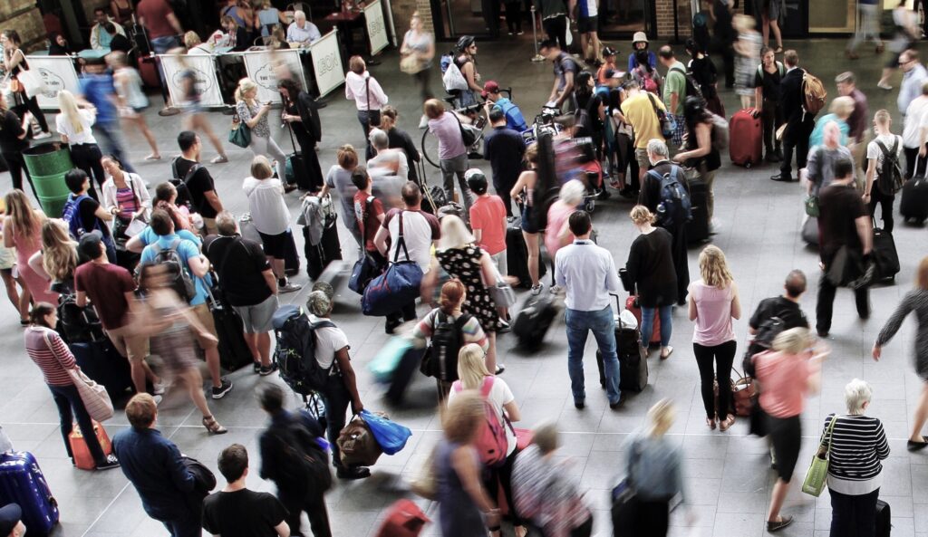 Viele Menschen an einem Bahnhof zu Stoßzeiten. Mittendrin eine Peson mit Fahrrad