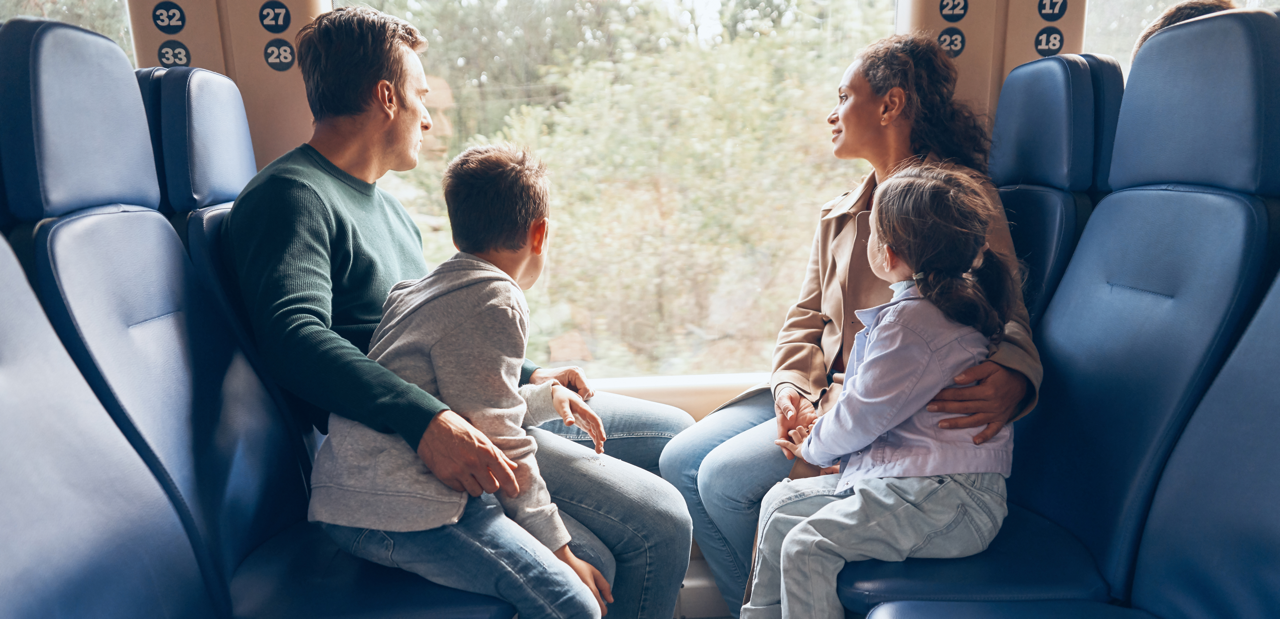 Eine Familie bestehend aus einem Mann, einer Frau und zwei Kindern sitzen gemeinsam in der Bahn.