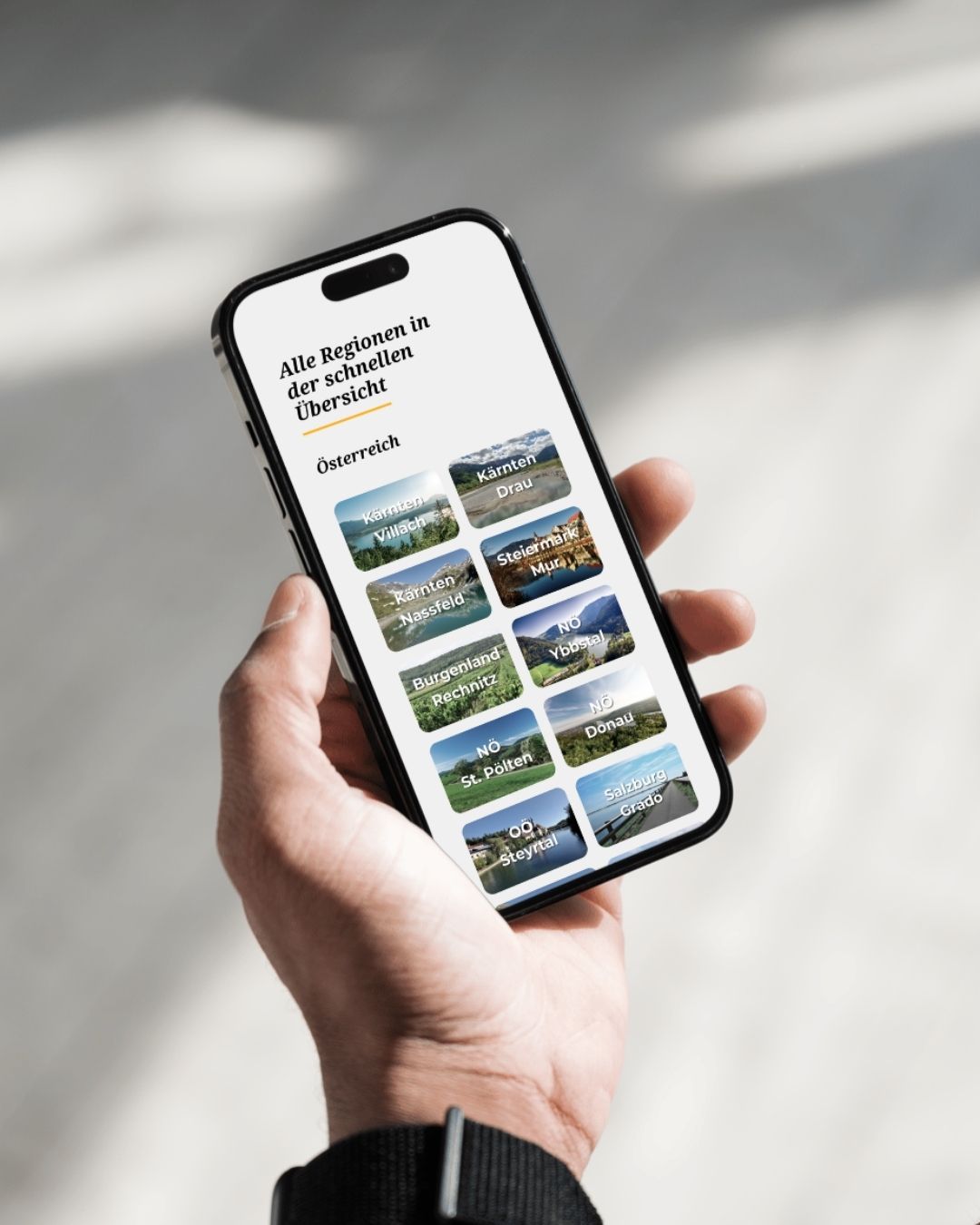 Hand mit Smartphone. Auf dem Display sieht man die Regionen-Übersicht im Radlbus-Guide
