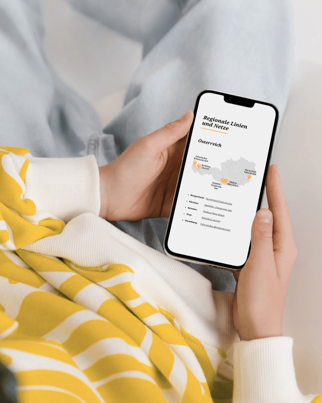 Person mit Smartphone. Bildschirm zeigt Österreich-Übersicht der regionalen Radbus-Linien