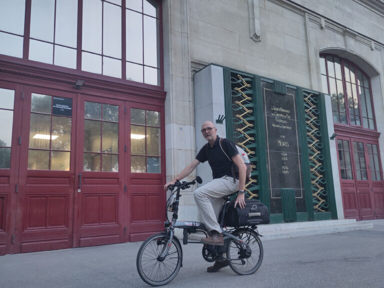 Michael mit seinem Koffer auf dem Faltrad. Eine Hand am Lenker, eine am Koffer beim Bahnhofswechsel in Paris